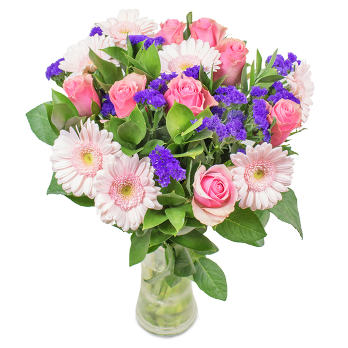 An exquisitely arranged bouquet of approximately eight soft pink roses, their petals in varying stages from tightly furled to gently unfurling, takes centre stage in this contemporary arrangement, presented in a crystal-clear vase atop a clean, white backdrop. About six pale pink gerbera daisies, each with broad, dainty petals radiating from subtle, almost ivory centres, complement the roses with their rounded formation, creating a graceful rhythm. At intermittent intervals, vivid purple filler flowers-reminiscent of the statice often found at Catford Broadway Market-bring a striking texture and a deeper hue, while lush, deep green foliage cradles the blooms in abundance, exuding freshness and vibrancy. Visible stems arch elegantly within the water-filled vase, reinforcing the sense of natural beauty that defines Catford's floral traditions. This arrangement embodies both celebration and heartfelt intent, making it ideal for birthdays, anniversaries, or as an uplifting floral accent in a Catford office or home, infusing the space with warmth, brightness, and enduring affection.